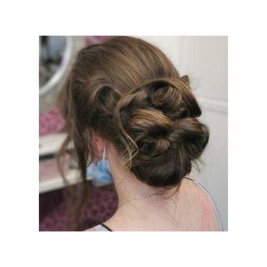 A woman’s hair styled in a decorative bun from the back.