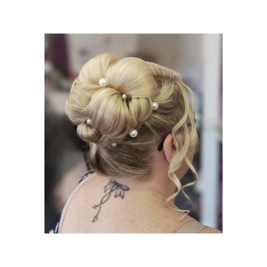 Elegant updo with blonde hair styled in a bun, adorned with pearls.